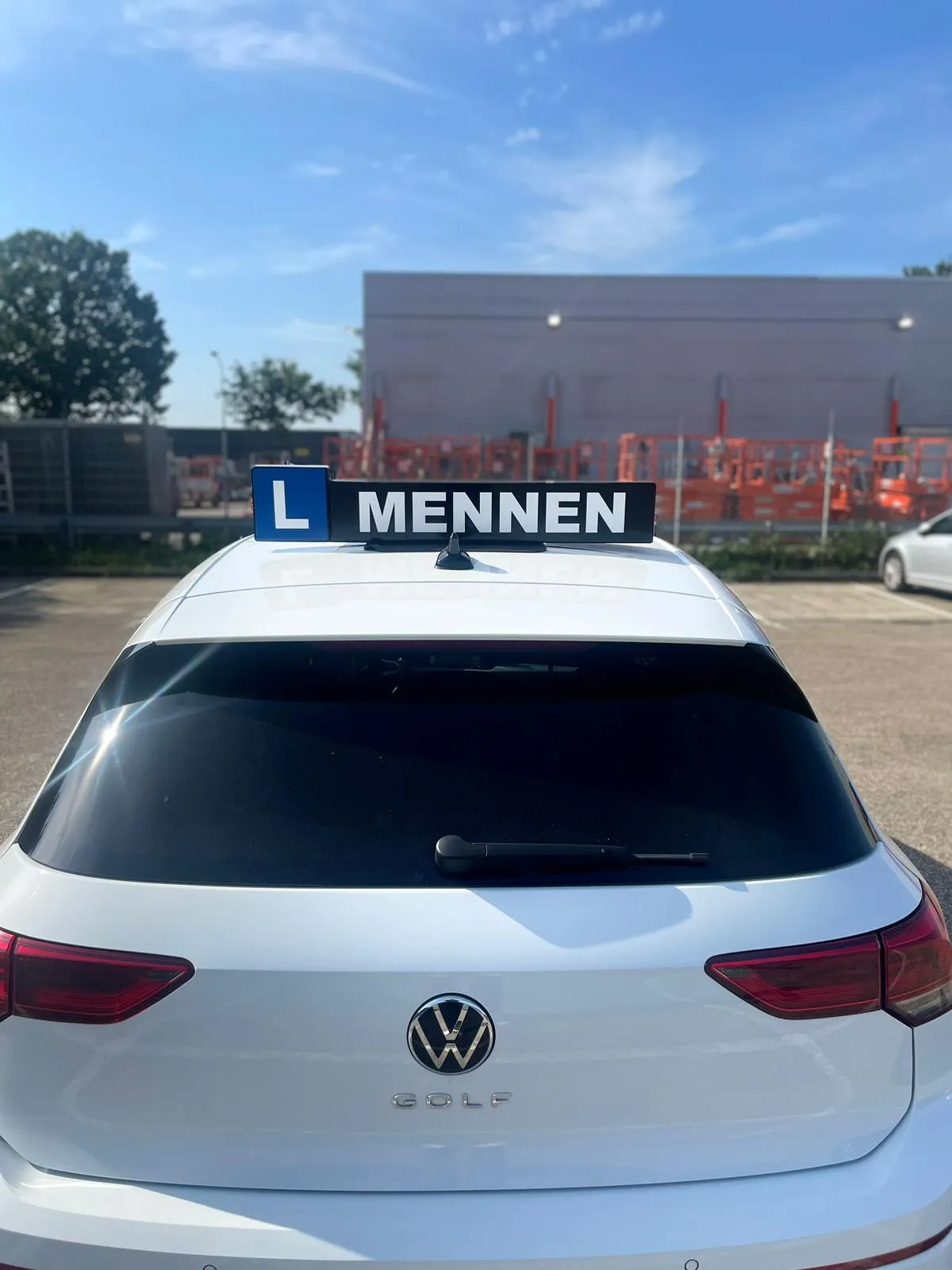 Rear of a white Volkswagen Golf with the blue L Mennen roof sign
