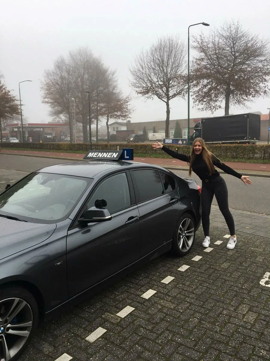 A student celebrating her pass next to a Mennen lesson car
